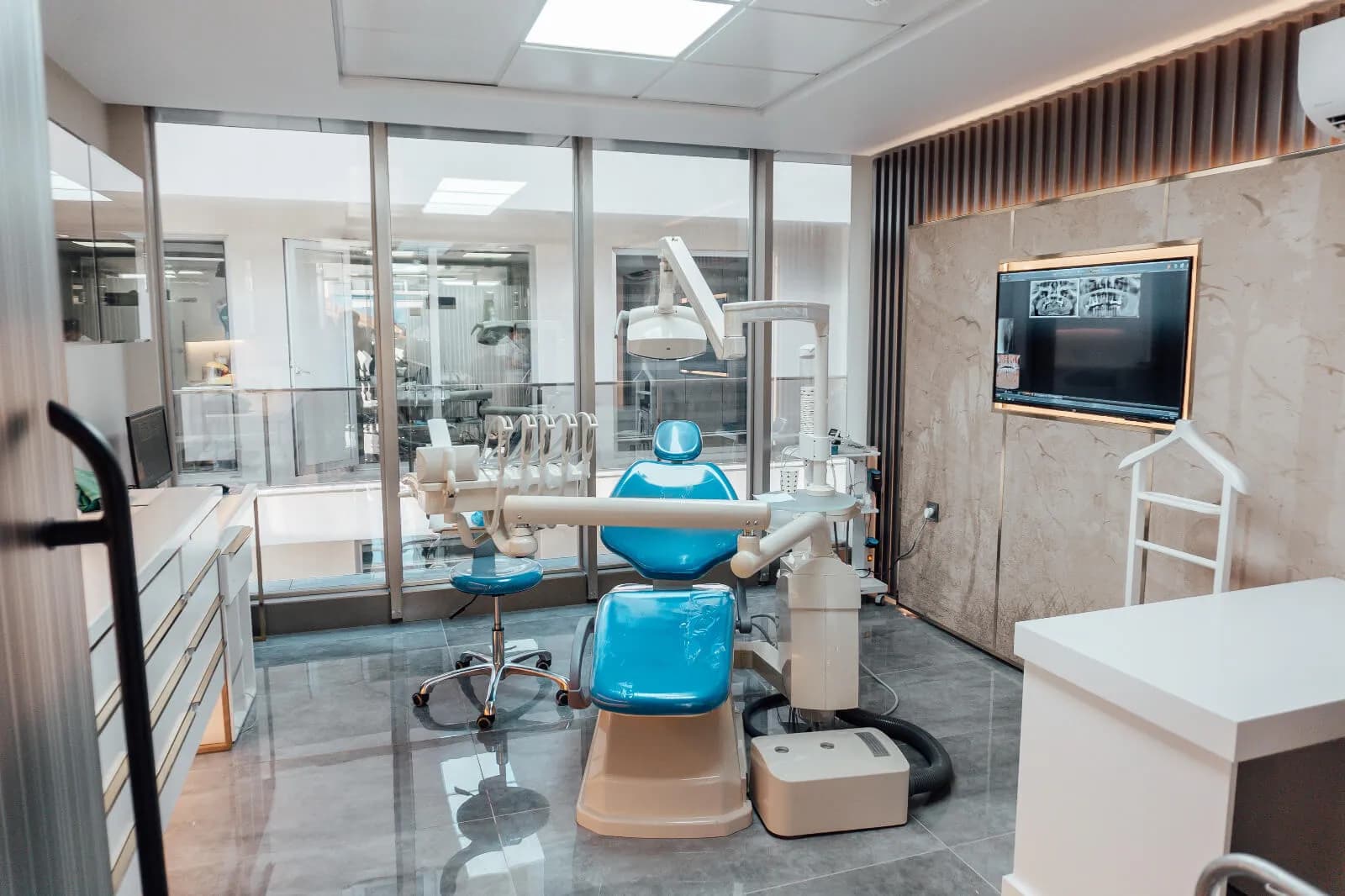 Een behandelkamer van Ballıpınar Dental met behandelstoel, operatielamp en een scherm met panoramaröntgenfoto's