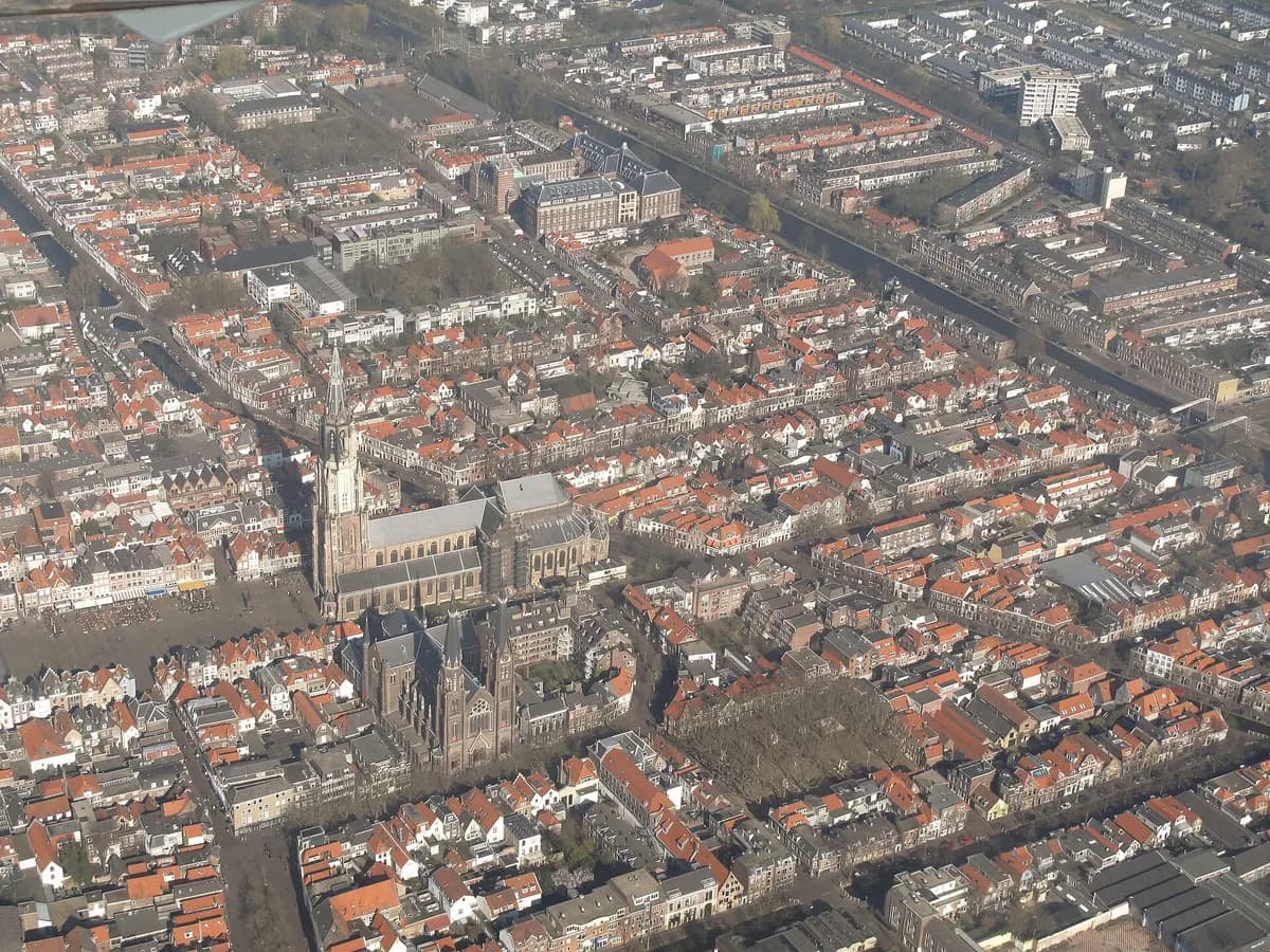 Delft: een gotische kerk met een hoge bakstenen toren boven de Markt